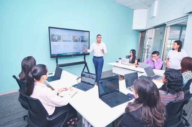 Team engaged in a presentation at a modern office using digital technology. Softwarelicenser og priser: En oversigt over modeller og omkostninger